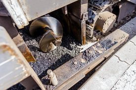Detail of industrial machinery working with asphalt. Tarmac road laying machine. Asphalt spreader.